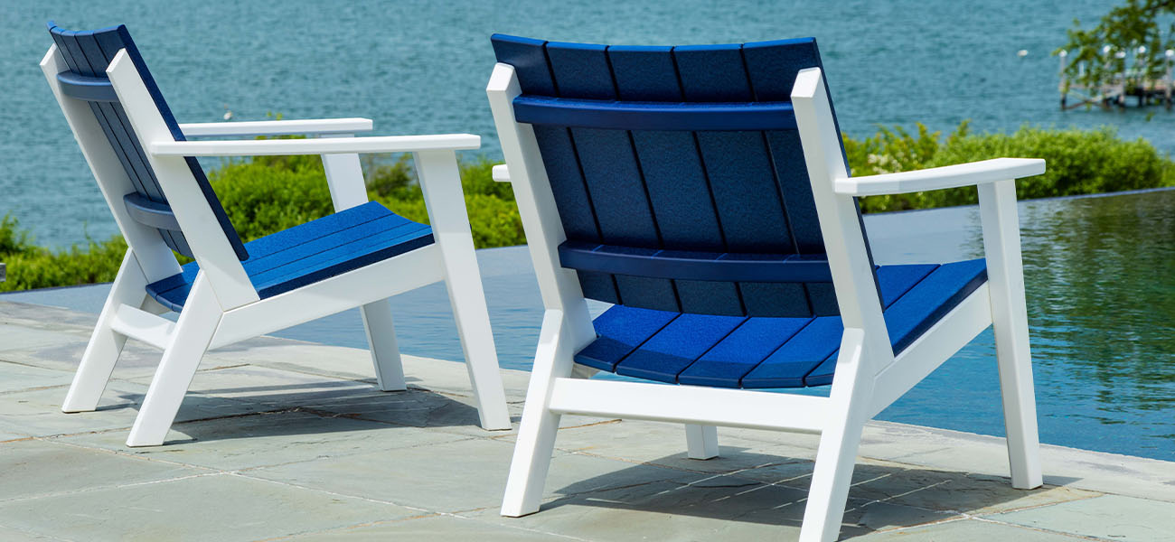 Pair of white and blue chairs next to a sparkling pool.