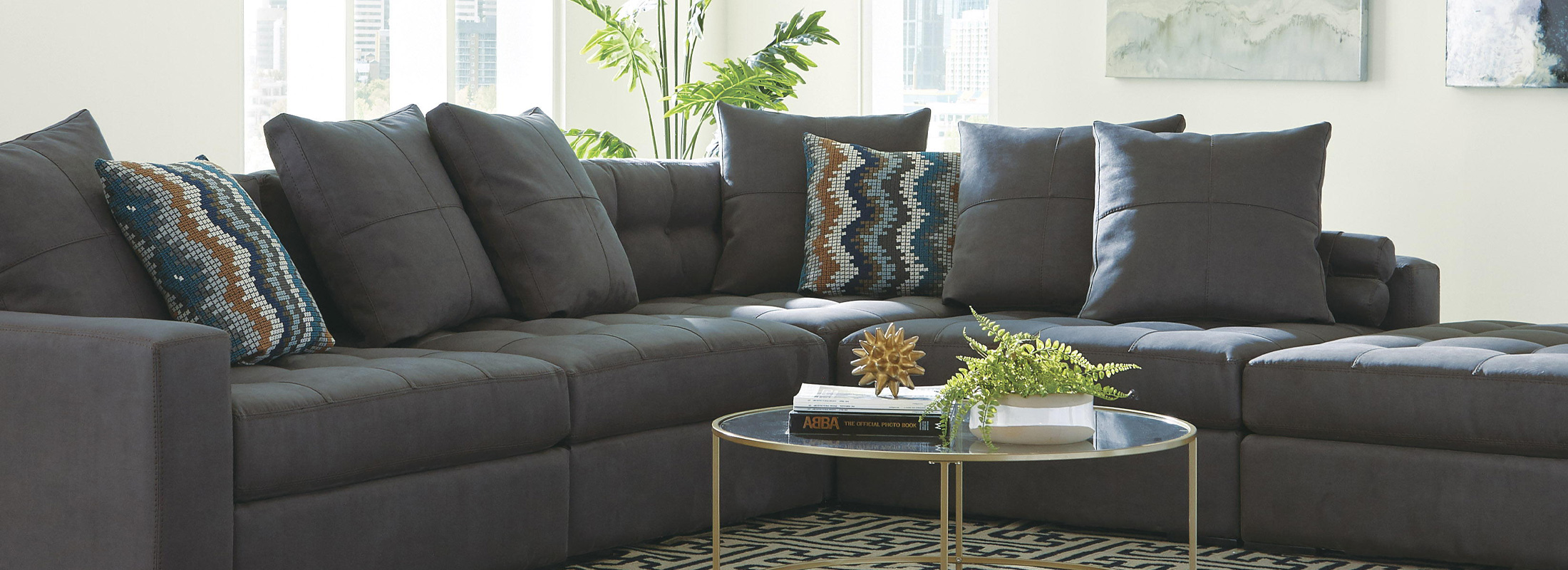 Dark grey sectional with 5 dark grey pillows and two patterened pillows