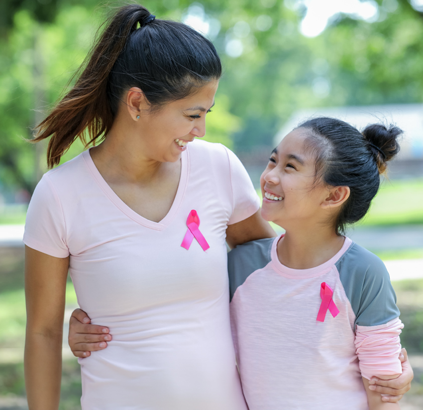 A woman and her young daughter are seen wearing pink ribbons, showcasing their bond and commitment to a meaningful cause.