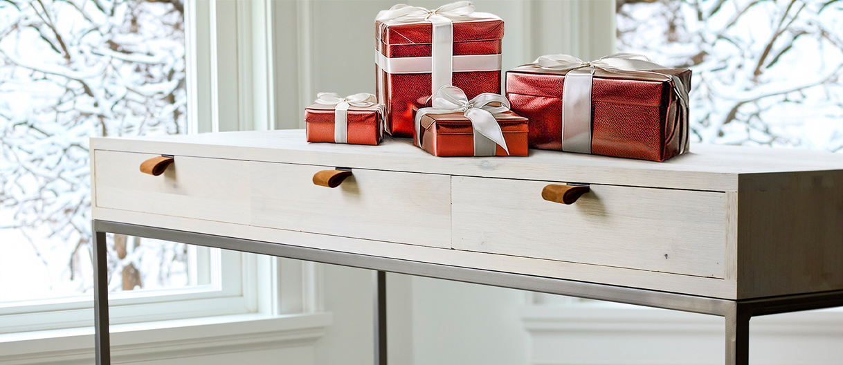  A stylish white console table featuring an arrangement of red and white wrapped gifts, perfect for holiday decor.