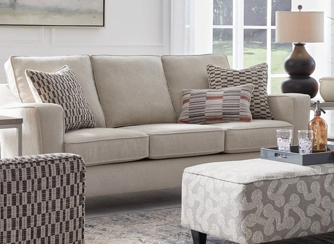 A well-furnished living room showcasing a plush couch, an ottoman, and a chic chair, perfect for relaxation and gatherings.