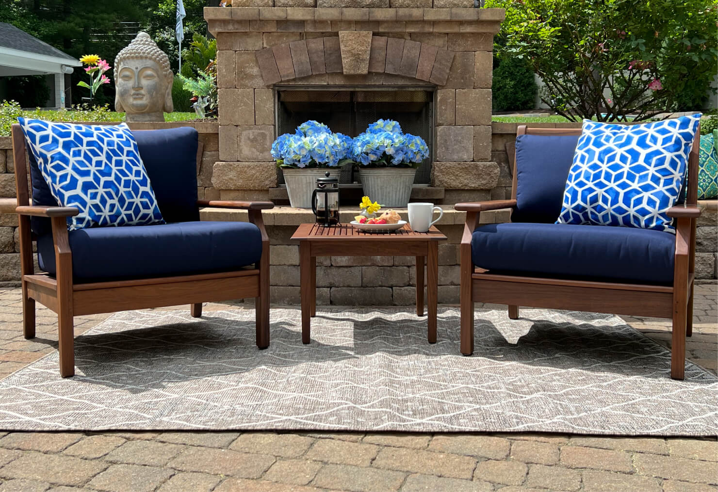 Outdoor seating area with two chairs, a fireplace, and decorative elements.