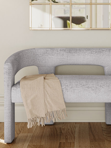 Gray bench with cozy blanket draped over it.