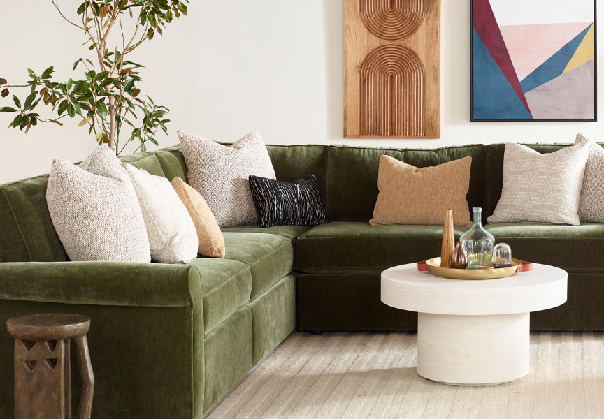 Stylish green sectional with throw pillows and coffee table.