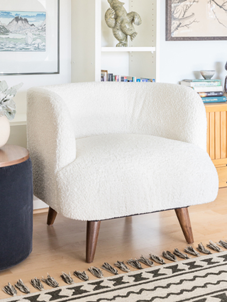  A white chair positioned in a cozy living room, complemented by a decorative rug beneath it.