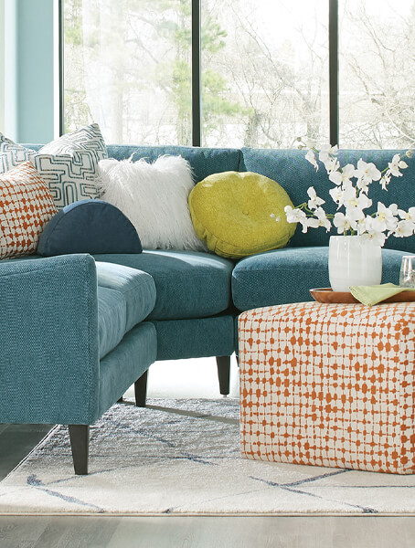 A blue sectional sofa adorned with vibrant orange pillows, creating a stylish and inviting living space.