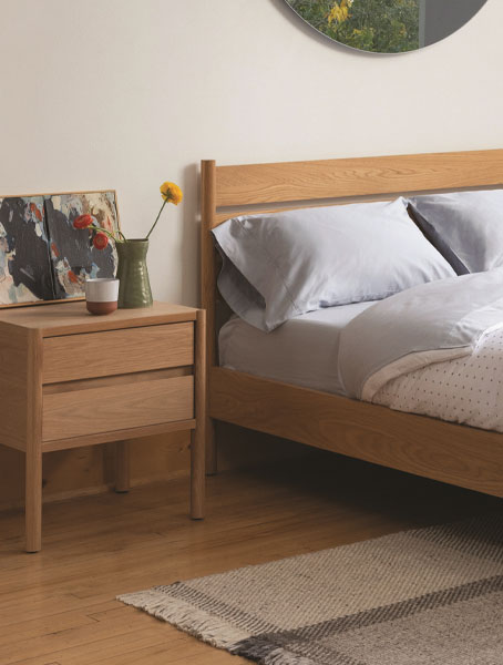 Cozy bedroom setup with wooden bed, nightstand, and mirror.