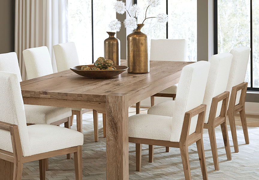 A dining table surrounded by white chairs, featuring a decorative vase at its center, creating an elegant dining atmosphere.