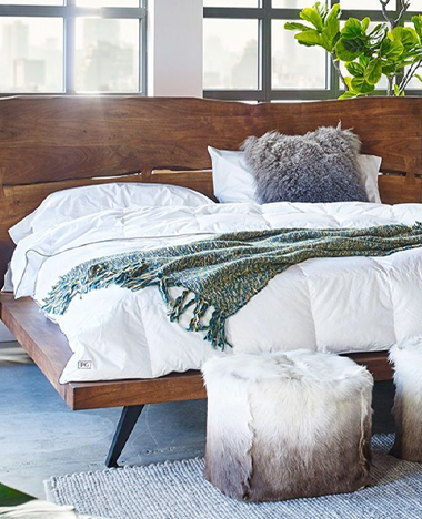 A cozy bed featuring a wooden headboard and a matching footstool, creating a warm and inviting bedroom atmosphere.