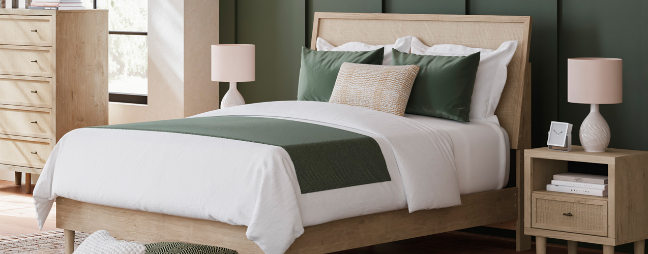 A cozy bed adorned with green and white bedding, complemented by a matching dresser in a serene bedroom setting.