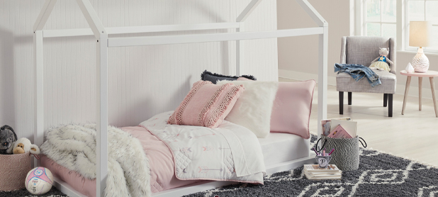 A white bed adorned with pink and white decorative elements, creating a soft and inviting atmosphere.