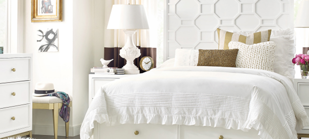 A serene white bedroom featuring a neatly made bed, a stylish dresser, and a matching nightstand.