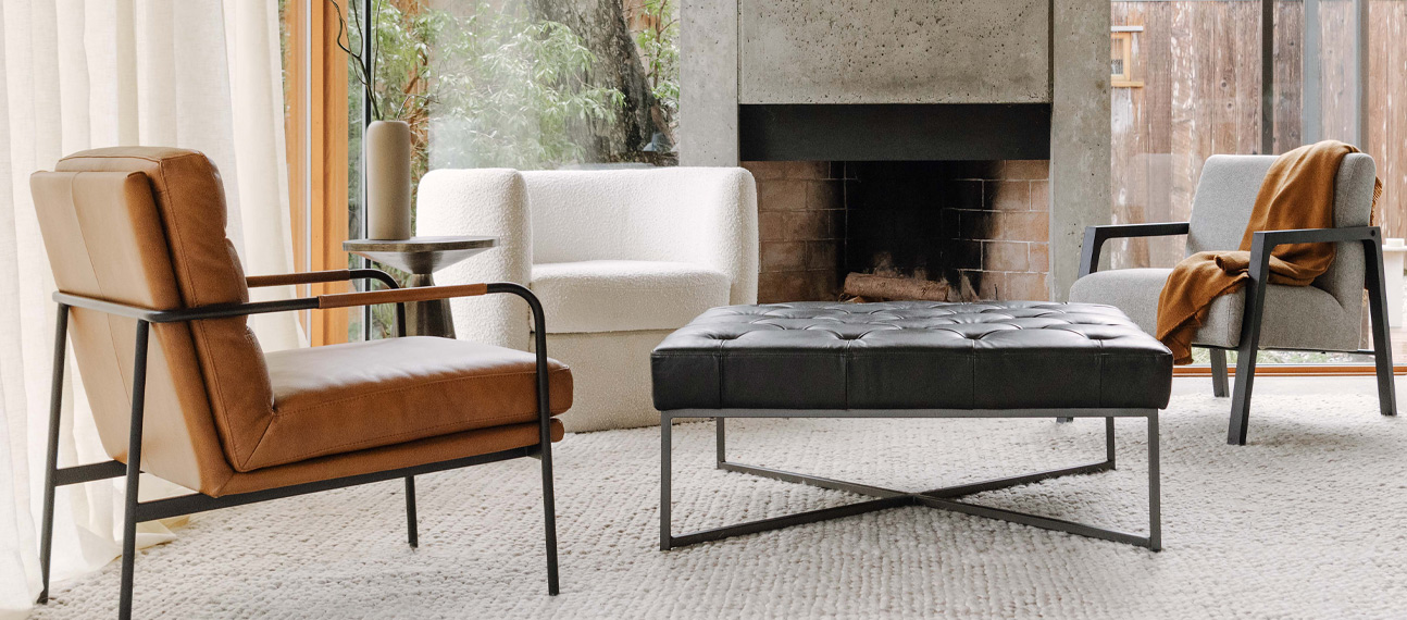 A cozy living room featuring a leather chair, an ottoman, and an additional chair, creating a comfortable seating area.