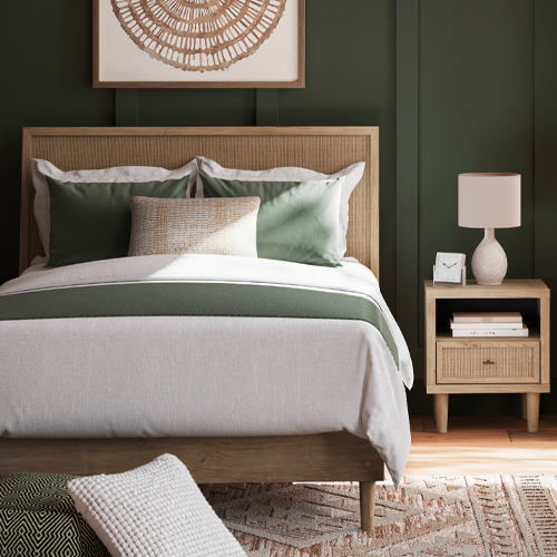 A cozy bedroom featuring green walls and a wooden headboard on the bed, creating a serene atmosphere.