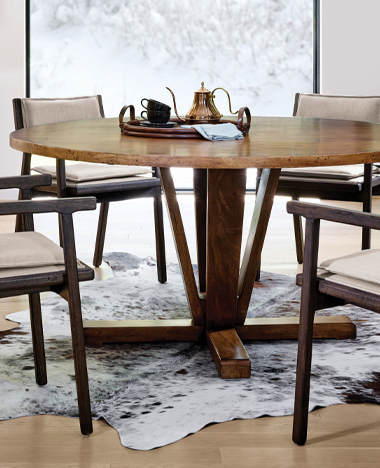 A round dining table surrounded by four elegant chairs, set for a cozy meal in a warm, inviting space.