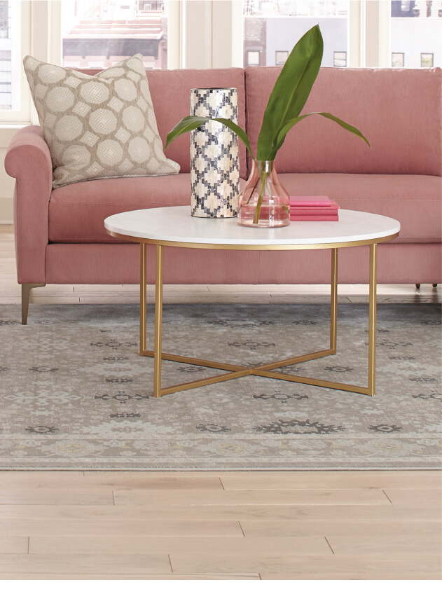 Customizable pink sofa in front of a white coffee table with small plant on top